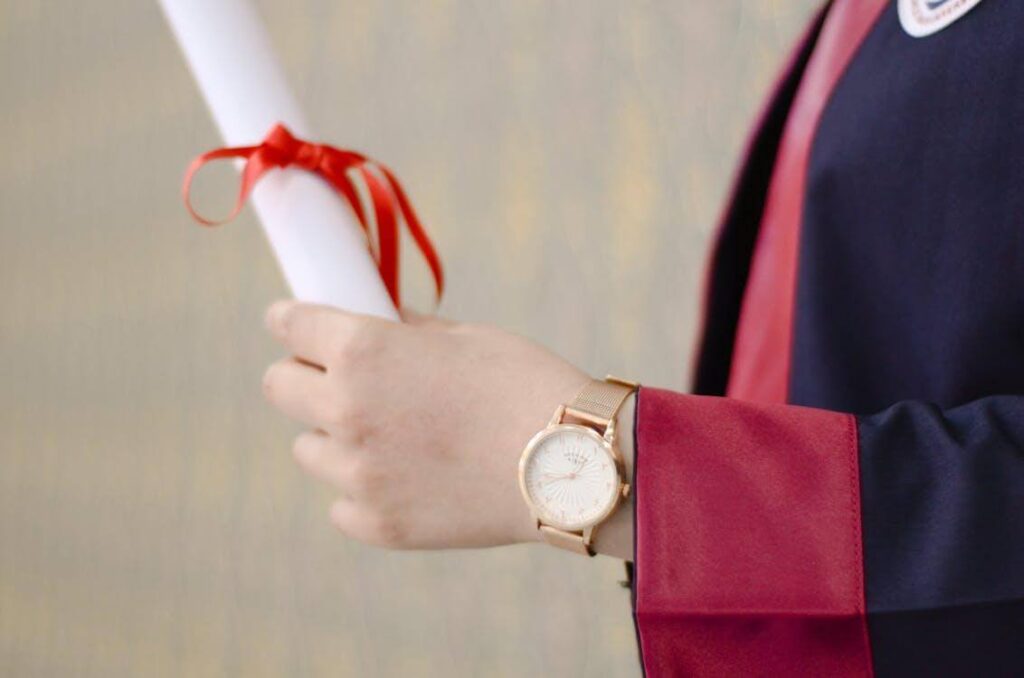 Nahaufnahme einer Person, die ein Diplom in der Hand hält.